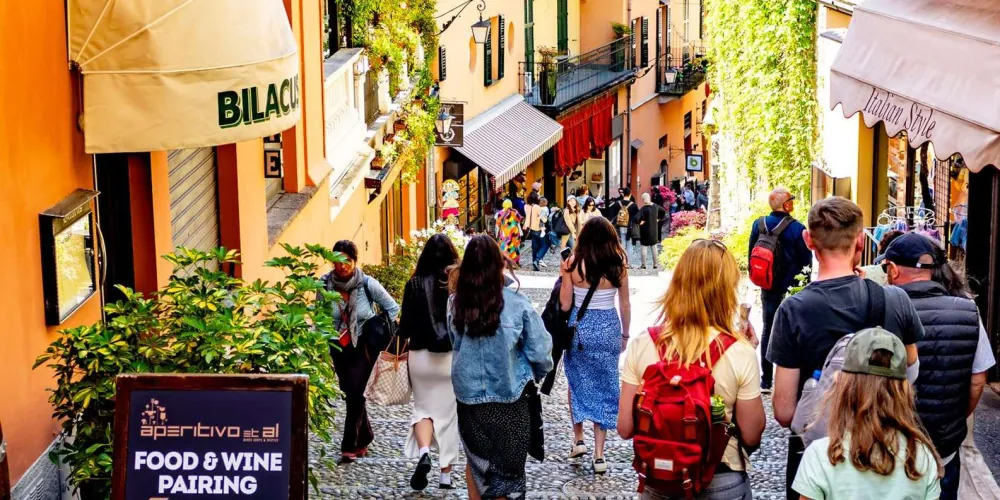 Visitors walking down Bellagio's stepped cobbled shopping street past cafés and boutiques